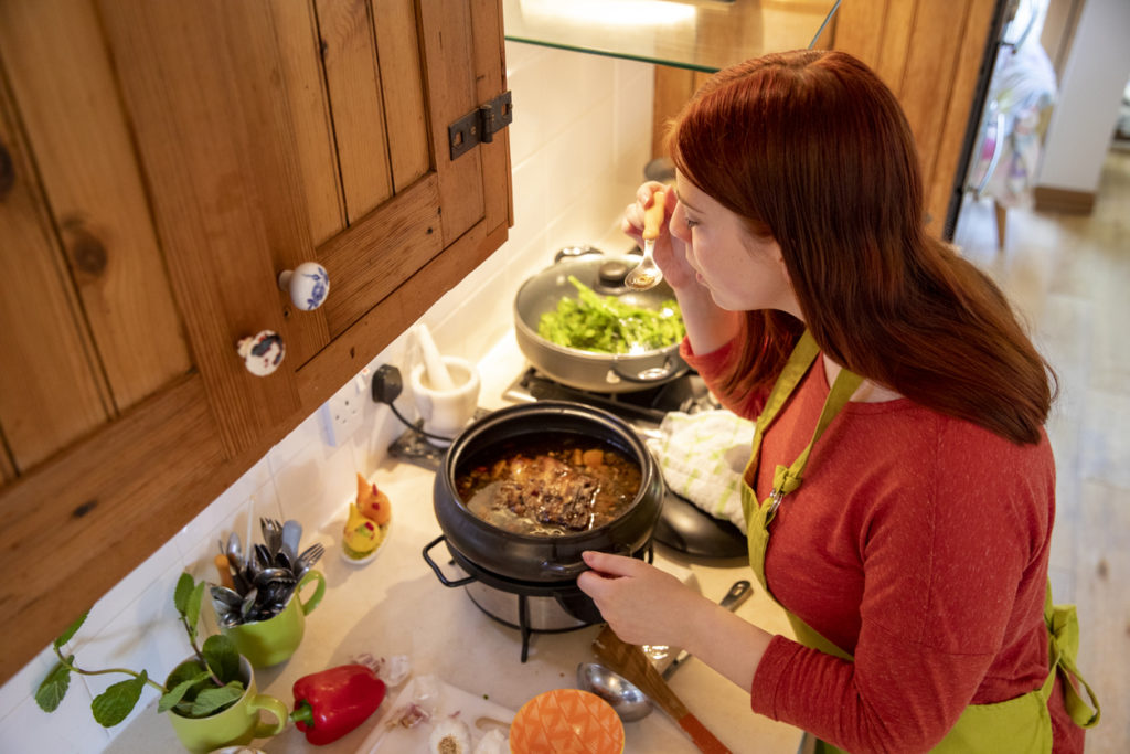 Woman prepares a meal in a slow cooker