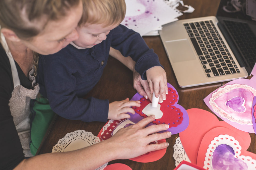 Mother and child make Valentine's Day crafts together.